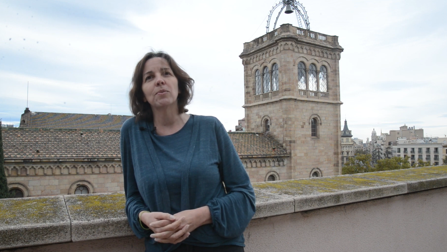 Mireia Farrús on the terrace of the CLiC laboratory, with views of the historic building of the University of Barcelona.