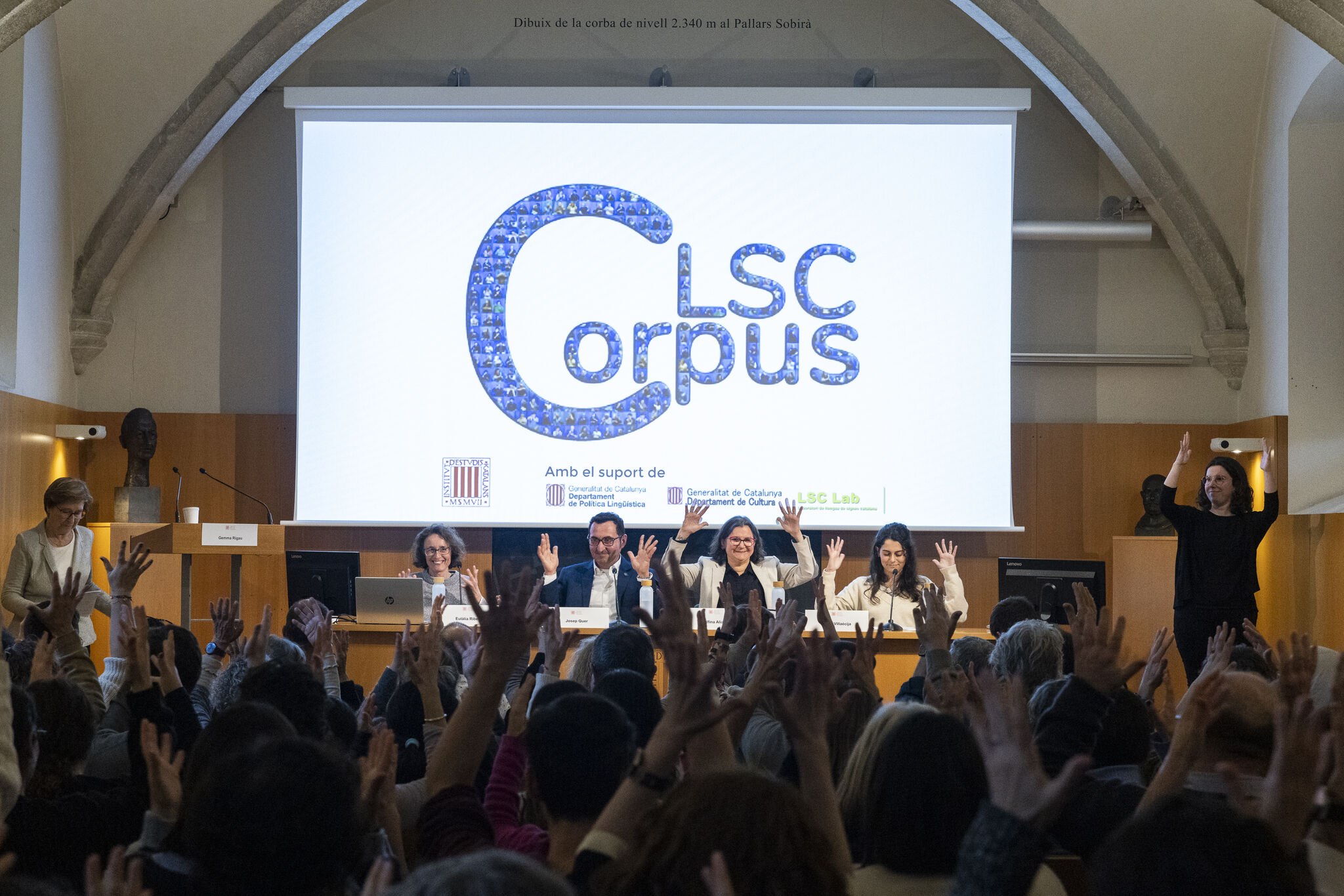 Presentación del Corpus LSC en IEC. La imagen muestra un aplauso en lengua de signos, con las manos alzadas