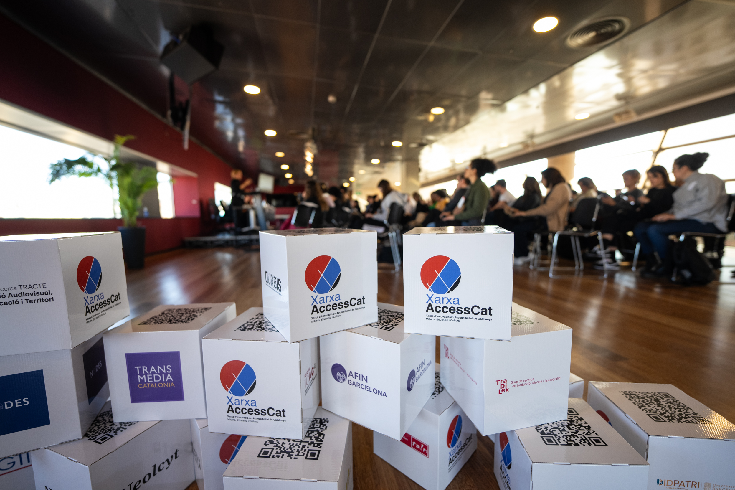 Cubs de cartró amb els logotips dels grups de recerca decoren el CCCB en la Jornada d'Innovació d'AccessCat.