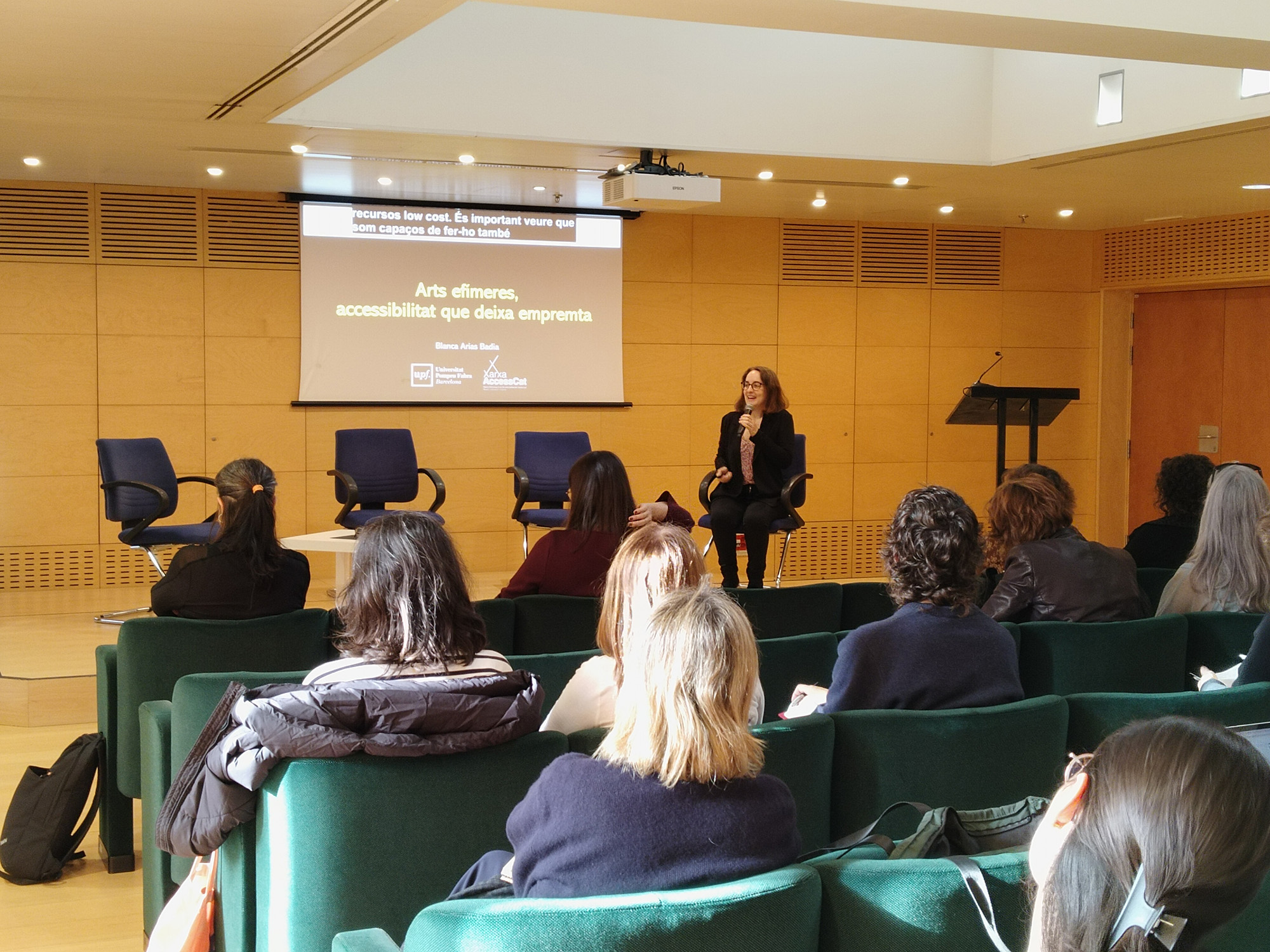 Blanca Arias parlant amb un micròfon a l'audiència de l'L’Institut Català de les Empreses Culturals de la Generalitat de Catalunya.